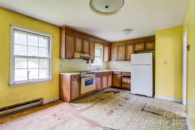 798 Wilson St, China Grove, NC 28023 - kitchen featuring freestanding refrigerator, under cabinet range hood, range, light countertops, and a baseboard heating unit