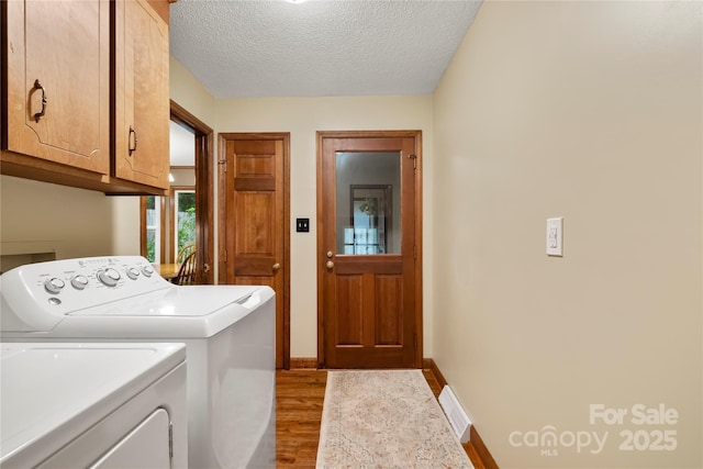 4848 Spicewood Dr, Charlotte, NC 28227 - laundry area with cabinet space, washer and dryer, light wood-style floors, a textured ceiling, and baseboards