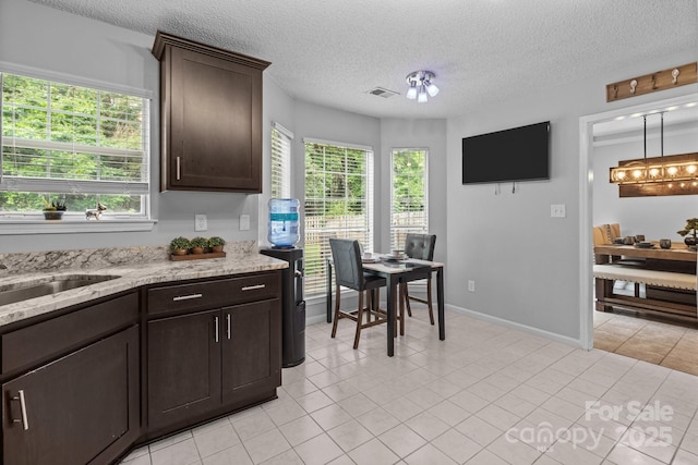 8906 Pickering Grove Ln, Charlotte, NC 28216 - kitchen featuring dark brown cabinets, light tile patterned floors, light stone counters, and a textured ceiling