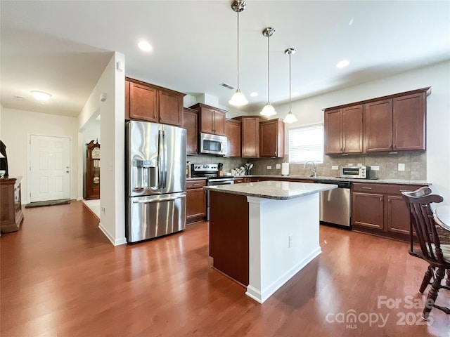 1228 Tranquil Falls Ln, Matthews, NC 28104 - kitchen with appliances with stainless steel finishes, dark wood finished floors, backsplash, decorative light fixtures, and a center island