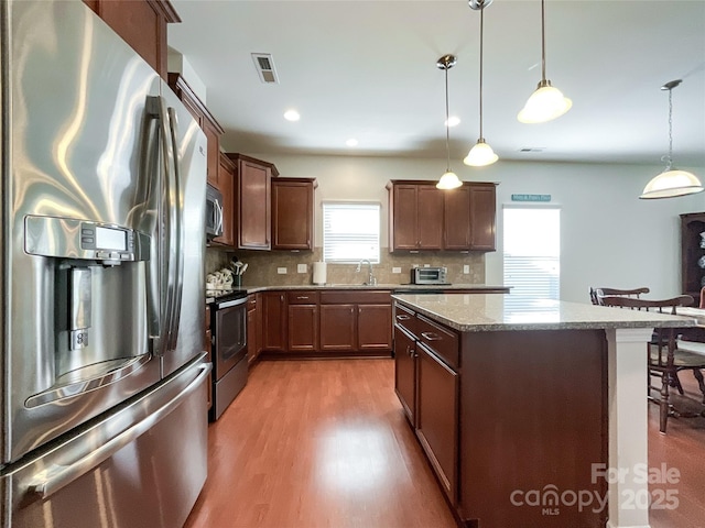 1228 Tranquil Falls Ln, Matthews, NC 28104 - kitchen featuring appliances with stainless steel finishes, a sink, wood finished floors, a center island, and tasteful backsplash