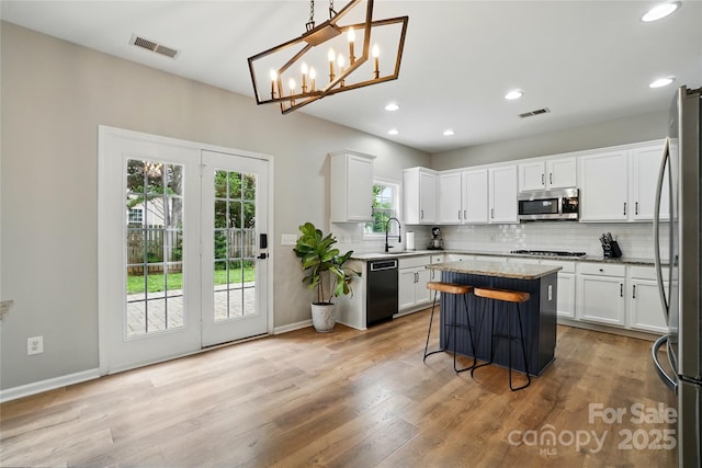 1522 Napa St NW, Concord, NC 28027 - kitchen featuring appliances with stainless steel finishes, tasteful backsplash, a kitchen island, a sink, and white cabinets