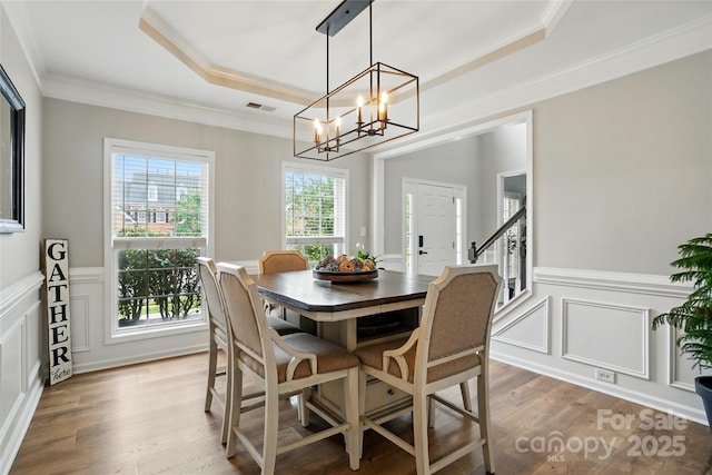 1522 Napa St NW, Concord, NC 28027 - dining room with a tray ceiling, a decorative wall, crown molding, wood finished floors, and wainscoting