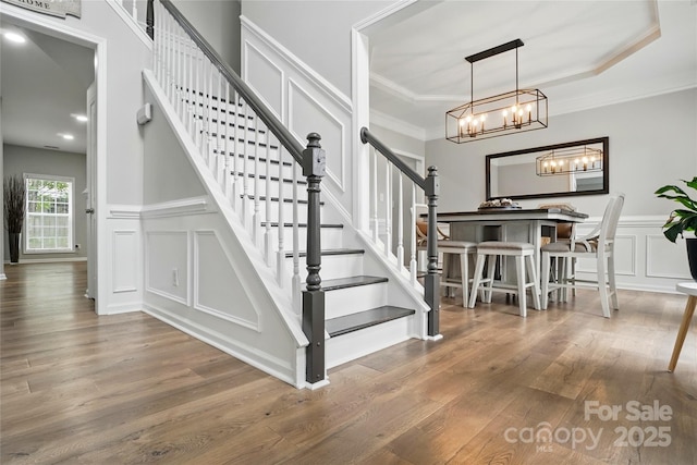 1522 Napa St NW, Concord, NC 28027 - staircase with a decorative wall, wood finished floors, a chandelier, ornamental molding, and wainscoting