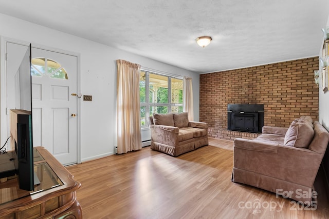 518 W School St, Maiden, NC 28650 - living area with light wood-type flooring, a baseboard radiator, a brick fireplace, baseboards, and brick wall