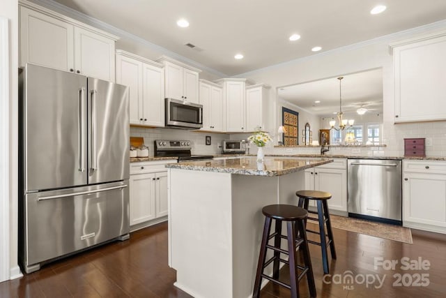2066 Vermount Way, Indian Land, SC 29707 - kitchen with appliances with stainless steel finishes, a chandelier, ornamental molding, dark wood-style floors, and a kitchen bar
