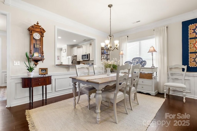 2066 Vermount Way, Indian Land, SC 29707 - dining space with a decorative wall, a chandelier, dark wood finished floors, crown molding, and wainscoting
