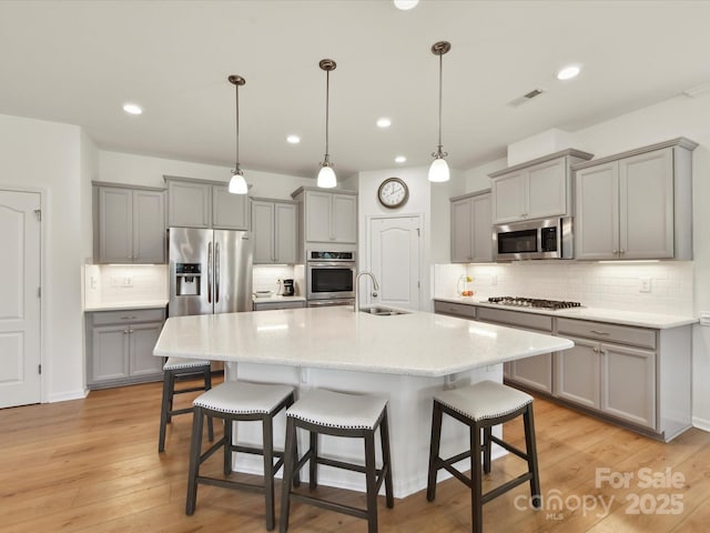 200 Sweet Briar Dr, Fort Mill, SC 29707 - kitchen featuring gray cabinetry, stainless steel appliances, a sink, a kitchen breakfast bar, and backsplash