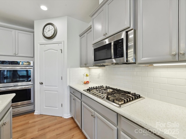 200 Sweet Briar Dr, Fort Mill, SC 29707 - kitchen with stainless steel appliances, gray cabinetry, light wood-style flooring, backsplash, and recessed lighting