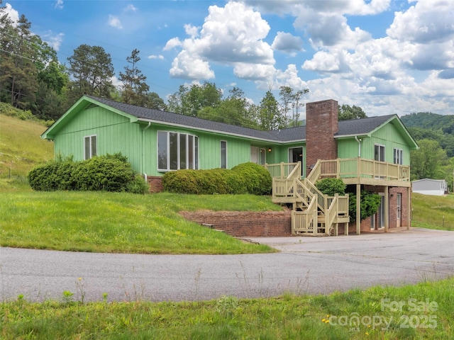 202 Terrell Rd, Clyde, NC 28721 - single story home with a chimney, a wooden deck, stairs, driveway, and board and batten siding