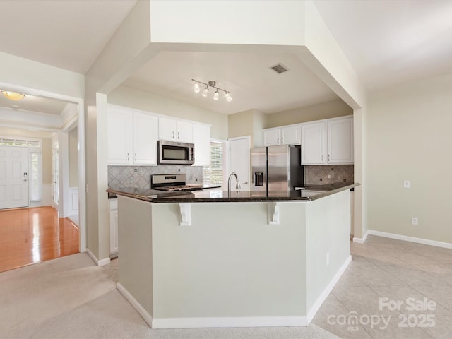 8603 Robinson Meadow Ct, Charlotte, NC 28277 - kitchen featuring appliances with stainless steel finishes, white cabinets, decorative backsplash, and a breakfast bar area
