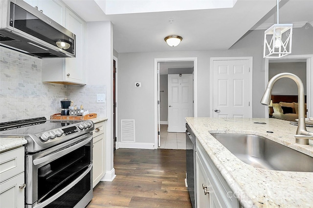 300 W 5th St Unit 003, Charlotte, NC 28202 - kitchen featuring appliances with stainless steel finishes, dark wood-style floors, backsplash, light stone counters, and white cabinetry