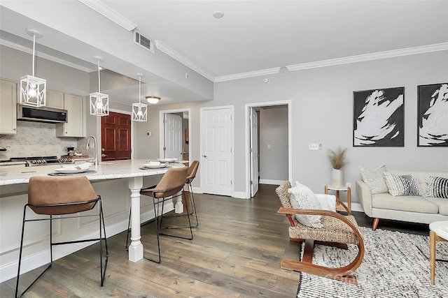 300 W 5th St Unit 003, Charlotte, NC 28202 - kitchen with crown molding, dark wood-style flooring, tasteful backsplash, a breakfast bar area, and stainless steel microwave