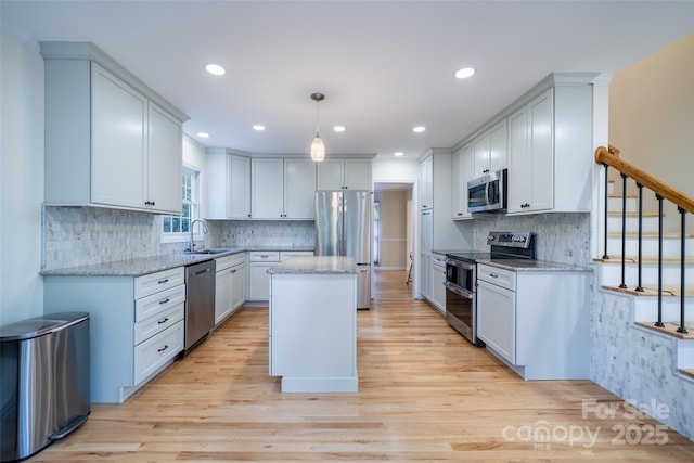 114 Coachmans Trl, Asheville, NC 28803 - kitchen featuring appliances with stainless steel finishes, a kitchen island, light wood-style flooring, light stone countertops, and recessed lighting