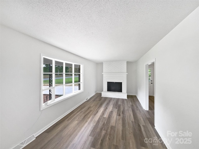 1224 Bethlehem Rd, Kings Mountain, NC 28086 - unfurnished living room with plenty of natural light, dark wood-style flooring, a textured ceiling, a brick fireplace, and baseboards