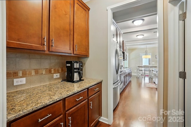 3106 Crosswind Dr, Fort Mill, SC 29707 - kitchen featuring wood finished floors, tasteful backsplash, light stone countertops, stainless steel fridge, and brown cabinetry