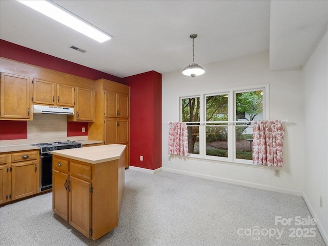 3327 Archdale Dr, Charlotte, NC 28210 - kitchen with gas range oven, under cabinet range hood, light countertops, baseboards, and hanging light fixtures