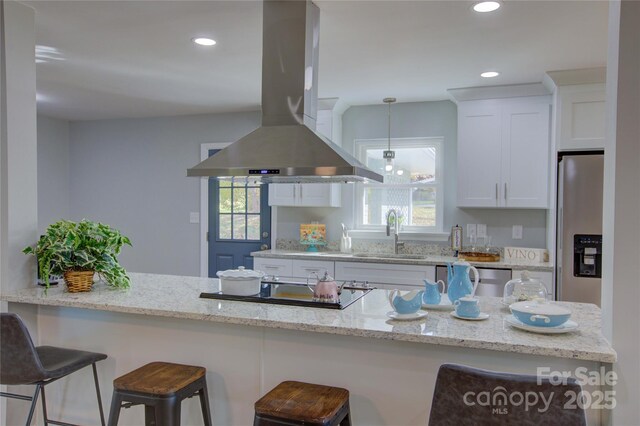 8607 Larchmont Cir, Charlotte, NC 28214 - kitchen featuring island exhaust hood, a sink, white cabinets, a kitchen breakfast bar, and light stone countertops