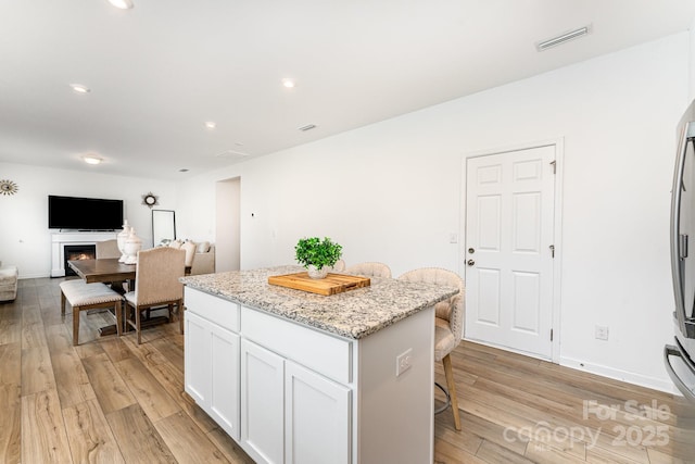 3077 Light Ridge Ct SW, Concord, NC 28027 - kitchen with a center island, a kitchen bar, light wood-style floors, white cabinetry, and recessed lighting