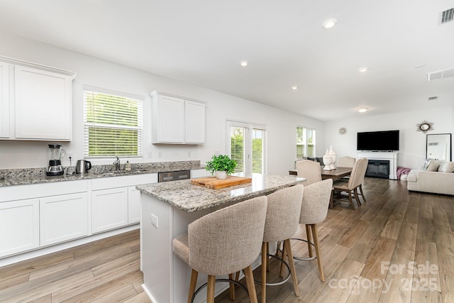 3077 Light Ridge Ct SW, Concord, NC 28027 - kitchen with a kitchen breakfast bar, white cabinetry, light stone countertops, a kitchen island, and open floor plan