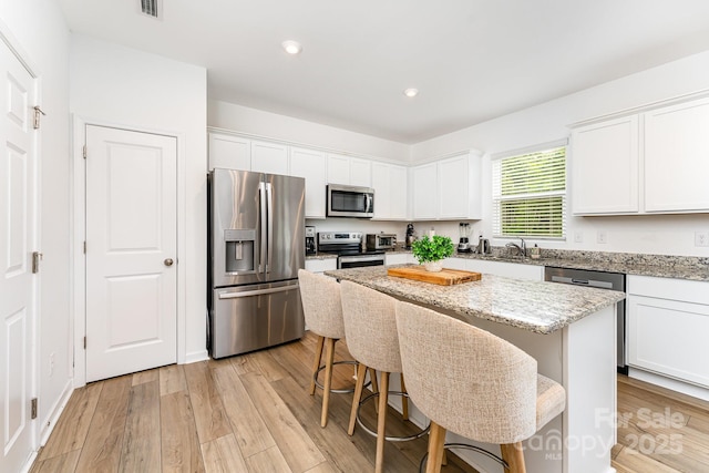 3077 Light Ridge Ct SW, Concord, NC 28027 - kitchen featuring appliances with stainless steel finishes, white cabinets, a center island, recessed lighting, and light wood-style floors