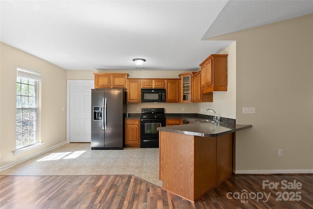 116 Dean Rd, Anderson, SC 29625 - kitchen featuring black appliances, brown cabinetry, a peninsula, a sink, and glass insert cabinets