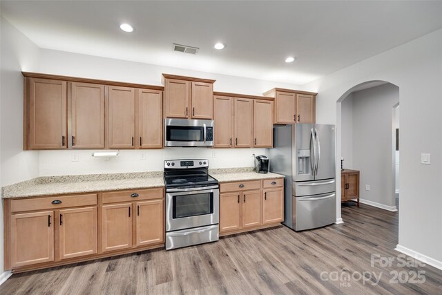 424 Castlebury Ct, Clover, SC 29710 - kitchen with stainless steel appliances, arched walkways, light wood-style flooring, light stone counters, and baseboards