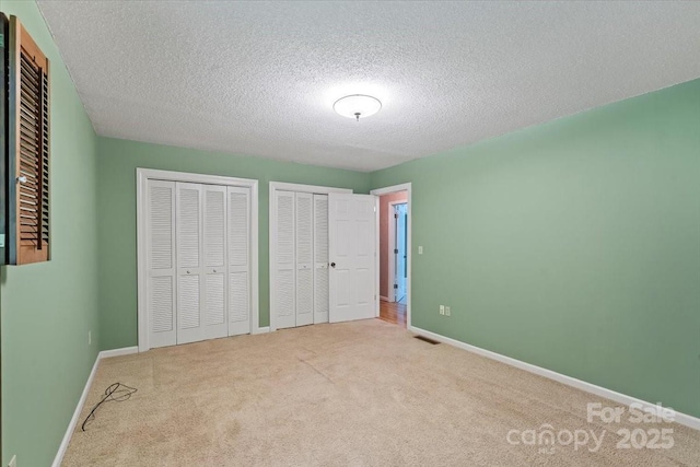 460 27th Avenue Cir NW, Hickory, NC 28601 - unfurnished bedroom featuring multiple closets, carpet floors, baseboards, and a textured ceiling