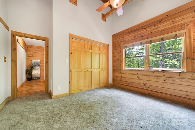 76 Isuhdavga Ct, Brevard, NC 28712 - unfurnished bedroom with a towering ceiling, carpet flooring, a closet, wooden walls, and baseboards