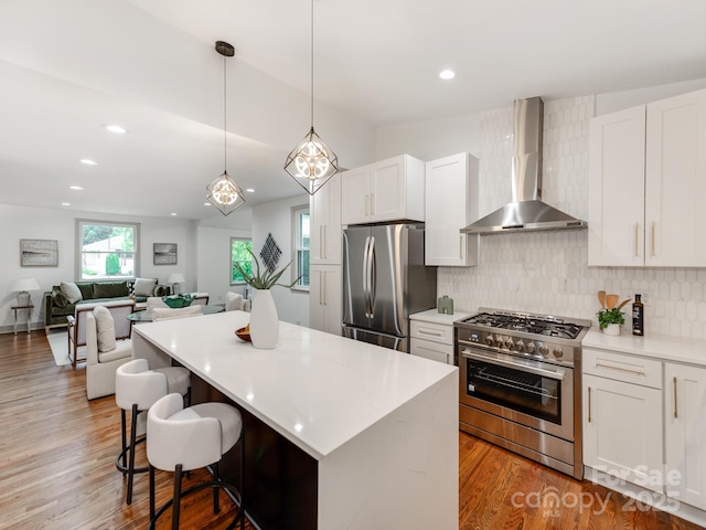 2114 Thurmond Pl, Charlotte, NC 28205 - kitchen with wall chimney exhaust hood, stainless steel appliances, decorative backsplash, wood finished floors, and light countertops