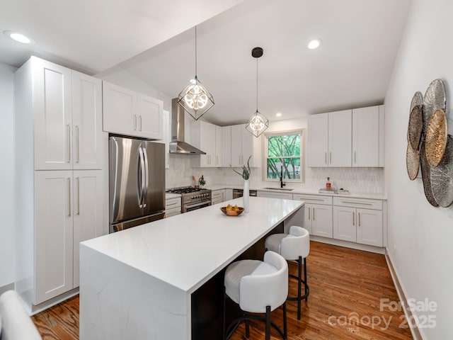 2114 Thurmond Pl, Charlotte, NC 28205 - kitchen featuring appliances with stainless steel finishes, tasteful backsplash, wall chimney exhaust hood, a kitchen island, and light countertops