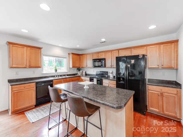 6532 Prosperity Commons Dr, Charlotte, NC 28269 - kitchen with black appliances, a sink, dark countertops, light wood-style flooring, and a breakfast bar area