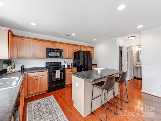 6532 Prosperity Commons Dr, Charlotte, NC 28269 - kitchen with black appliances, a sink, a breakfast bar, a center island, and wood finished floors