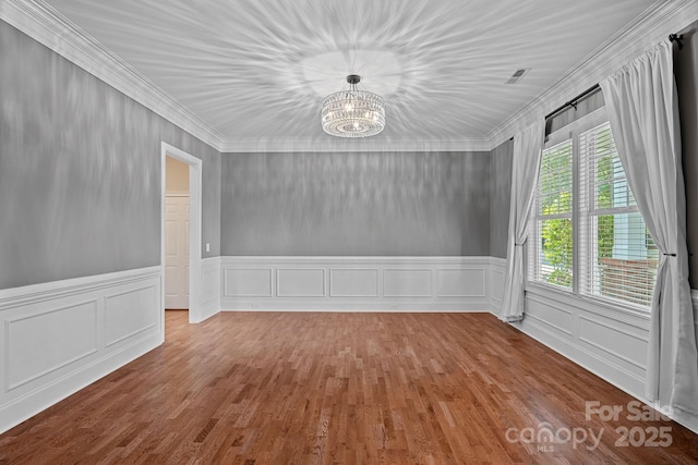 16909 Red Cow Rd, Charlotte, NC 28277 - unfurnished dining area with a chandelier, crown molding, wood finished floors, a wainscoted wall, and a decorative wall