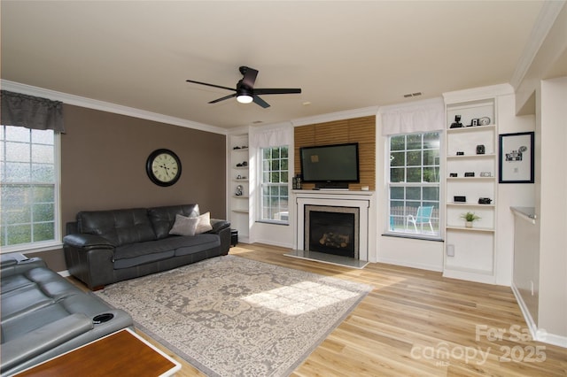 4001 Brook Valley Run, Monroe, NC 28110 - living area featuring wood finished floors, a ceiling fan, crown molding, a fireplace with raised hearth, and healthy amount of natural light