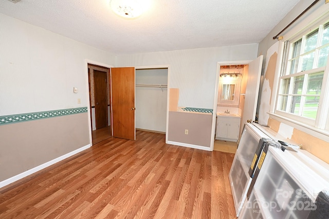 2625 Glenn St, Newton, NC 28658 - unfurnished bedroom with light wood finished floors, a sink, a textured ceiling, a closet, and baseboards