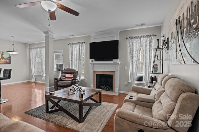 2233 Sonoma Valley Dr, Charlotte, NC 28214 - living area with ceiling fan, wood finished floors, a fireplace with raised hearth, and decorative columns