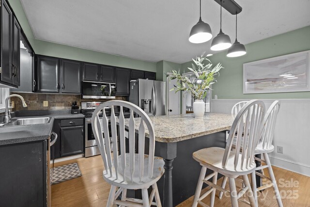 4043 Windward Dr, Tega Cay, SC 29708 - kitchen featuring a sink, stainless steel appliances, dark cabinets, backsplash, and a breakfast bar area