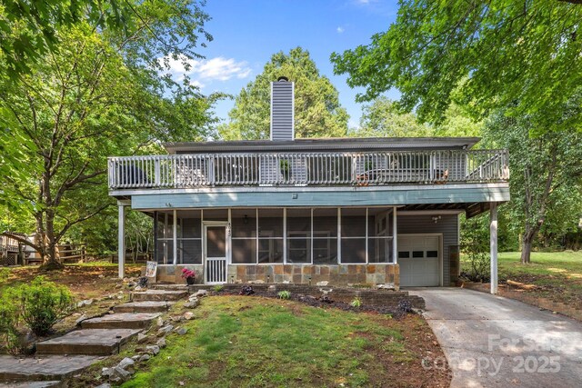 4043 Windward Dr, Tega Cay, SC 29708 - rear view of property featuring a sunroom, a garage, concrete driveway, a chimney, and a lawn