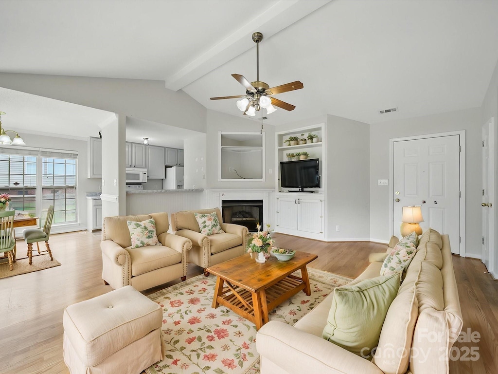 1148 Stallings Rd, Matthews, NC 28104 - living room with light wood-type flooring, a ceiling fan, a glass covered fireplace, built in features, and baseboards
