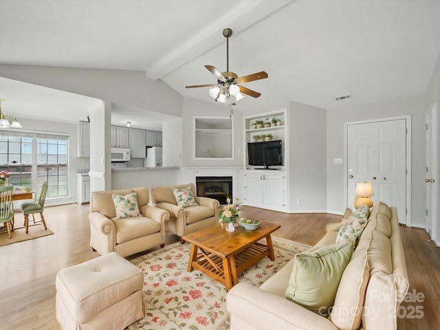 1148 Stallings Rd, Matthews, NC 28104 - living room with light wood-type flooring, a ceiling fan, a glass covered fireplace, built in features, and baseboards