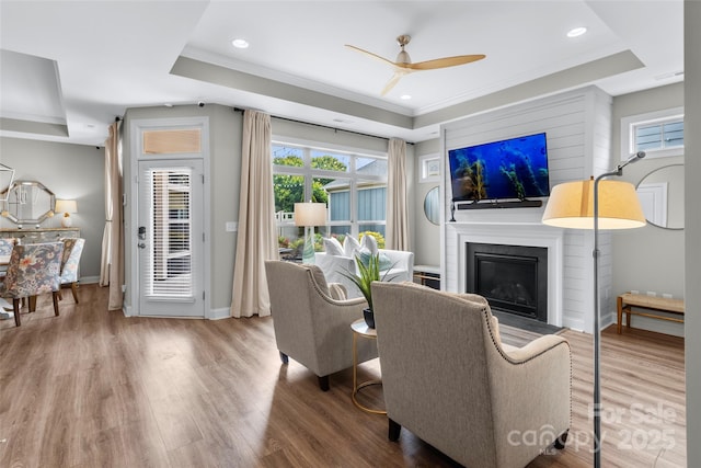 1712 Askern Ct, Waxhaw, NC 28173 - living room featuring a tray ceiling, a glass covered fireplace, ceiling fan, ornamental molding, and wood finished floors