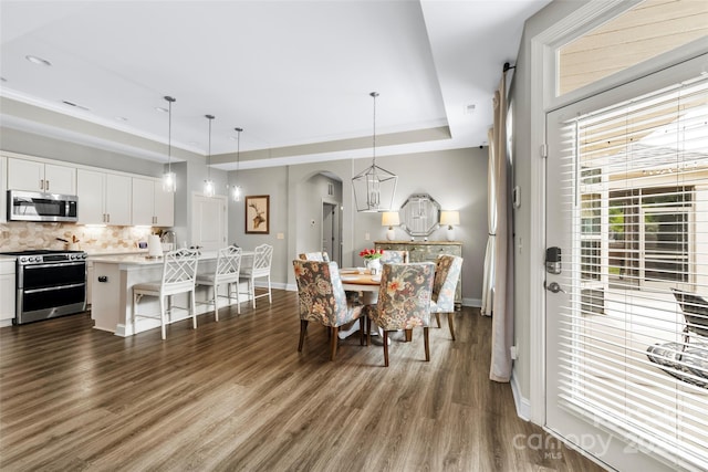 1712 Askern Ct, Waxhaw, NC 28173 - dining space with arched walkways, dark wood-style floors, baseboards, and a tray ceiling