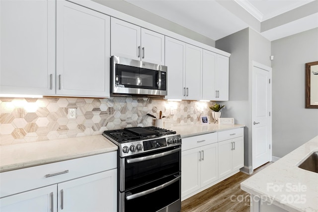 1712 Askern Ct, Waxhaw, NC 28173 - kitchen with stainless steel appliances, wood finished floors, white cabinetry, light stone countertops, and ornamental molding