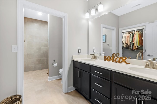 1712 Askern Ct, Waxhaw, NC 28173 - full bathroom with double vanity, toilet, a walk in closet, a tile shower, and baseboards