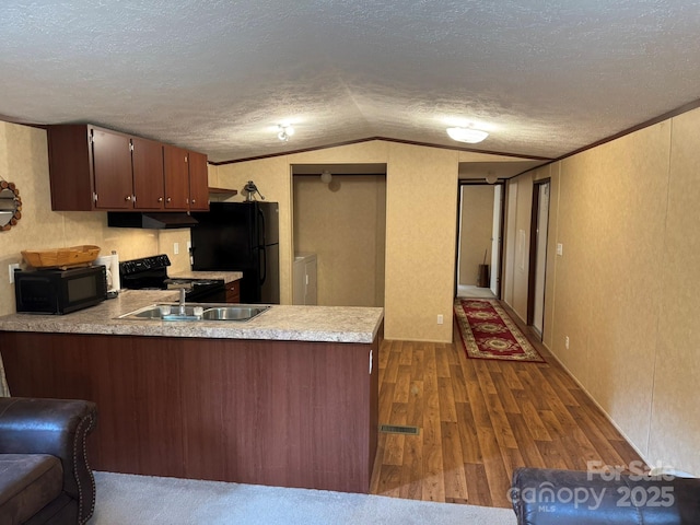 kitchen with black appliances, a peninsula, light countertops, dark wood-style floors, and a sink