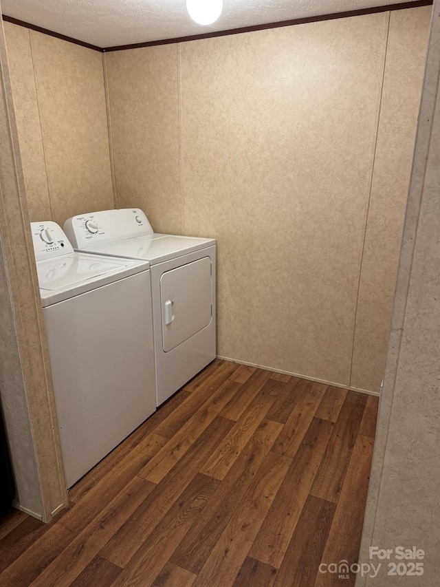 laundry room featuring independent washer and dryer, hardwood / wood-style flooring, a decorative wall, a textured ceiling, and ornamental molding