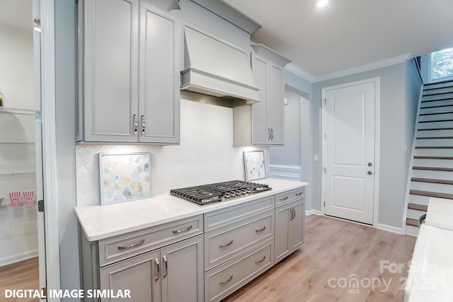 9842 Quercus Ln, Huntersville, NC 28078 - kitchen featuring custom exhaust hood, gray cabinets, decorative backsplash, light wood-style flooring, and crown molding