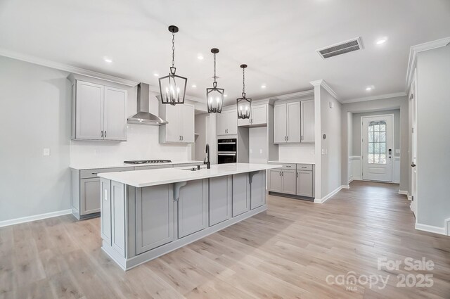 9934 Cask Way, Huntersville, NC 28078 - kitchen featuring wall chimney exhaust hood, gray cabinets, stovetop, crown molding, and an island with sink