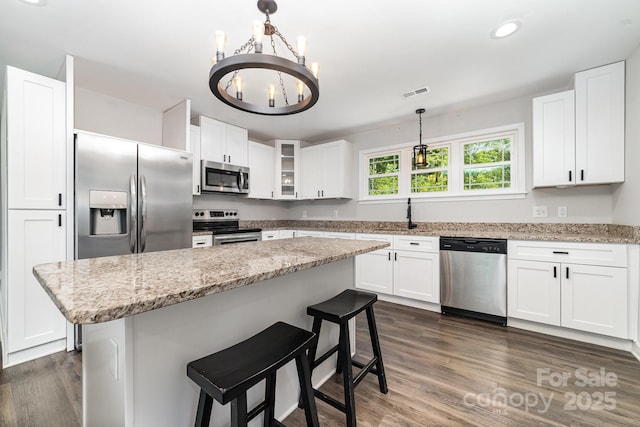 1632 Charles Raper Jonas Hwy, Mount Holly, NC 28120 - kitchen featuring stainless steel appliances, a chandelier, white cabinetry, a breakfast bar area, and glass insert cabinets